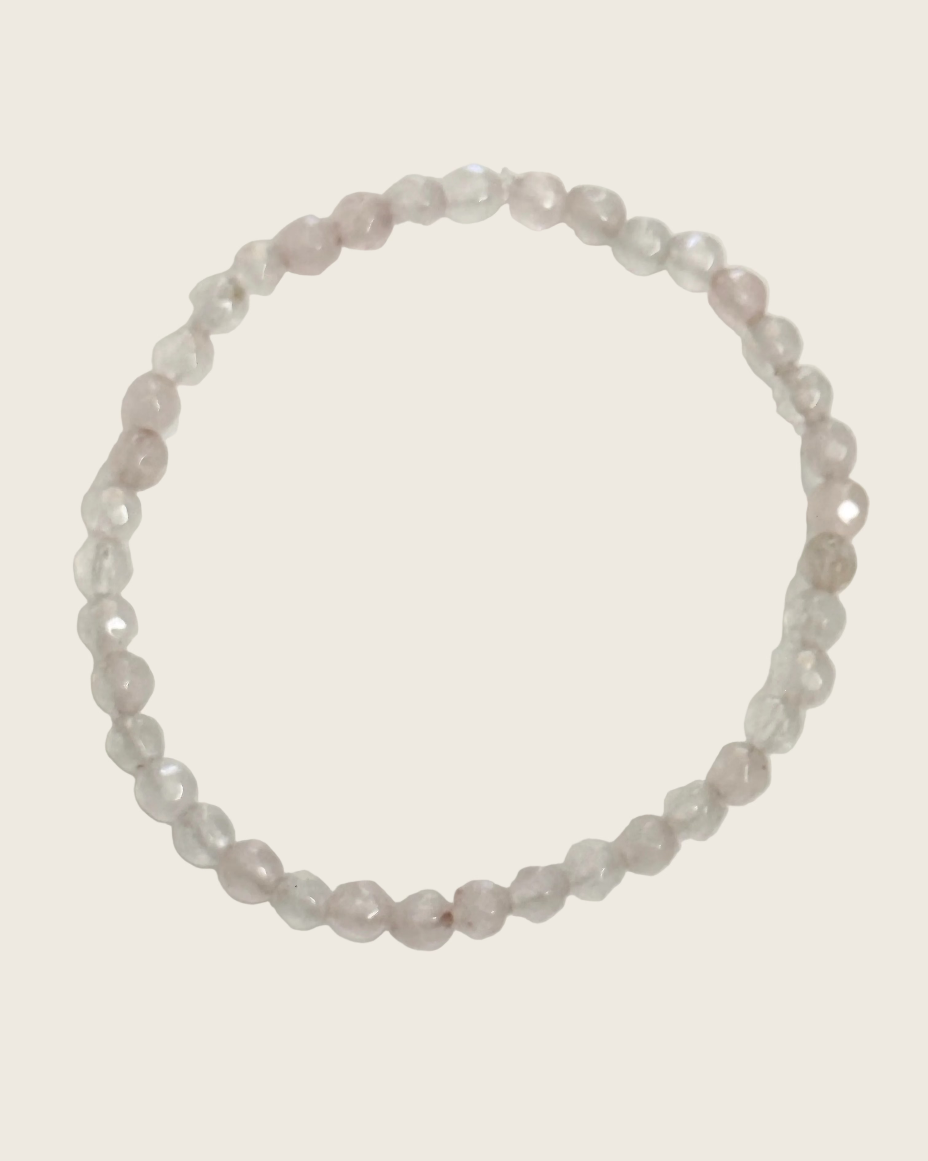A beaded stretch bracelet made of faceted, translucent pale pink and clear beads, arranged in a circle on a plain white background.