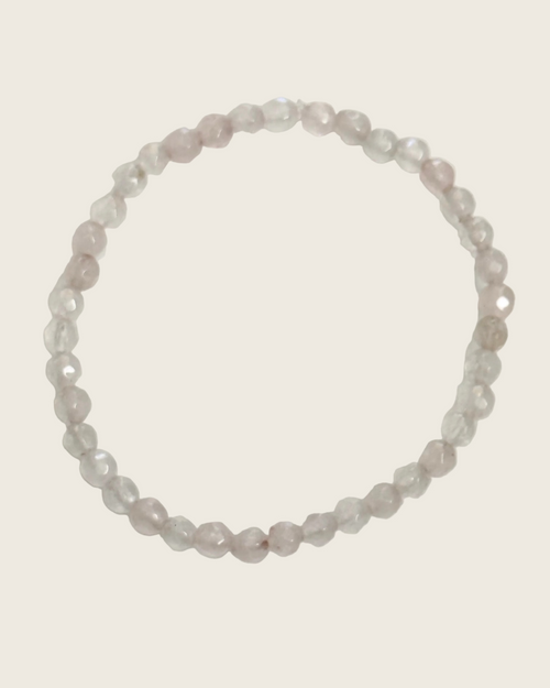 A beaded stretch bracelet made of faceted, translucent pale pink and clear beads, arranged in a circle on a plain white background.