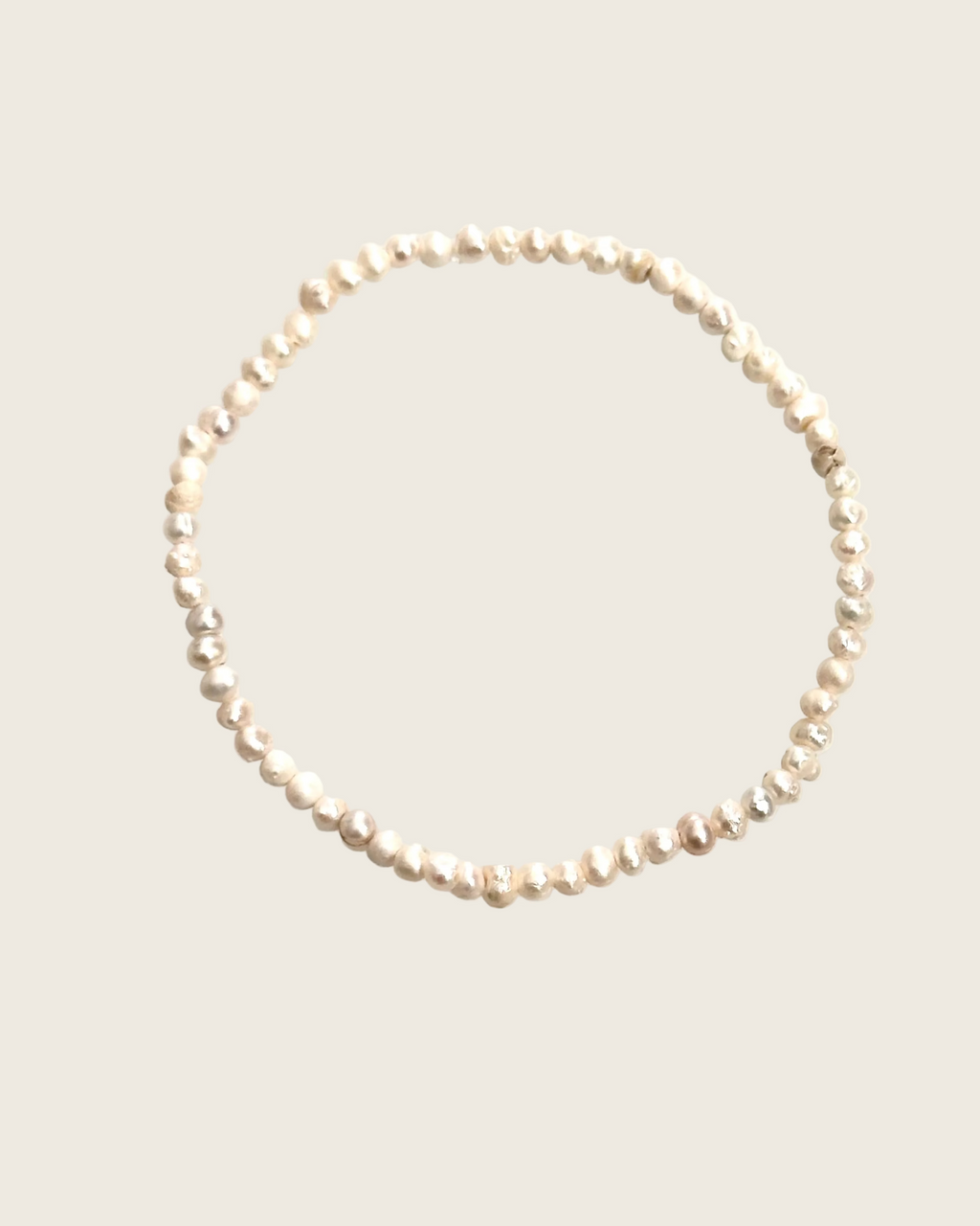 A single strand of irregular, lustrous pearl-like beads arranged in a loose circle on a plain white background.