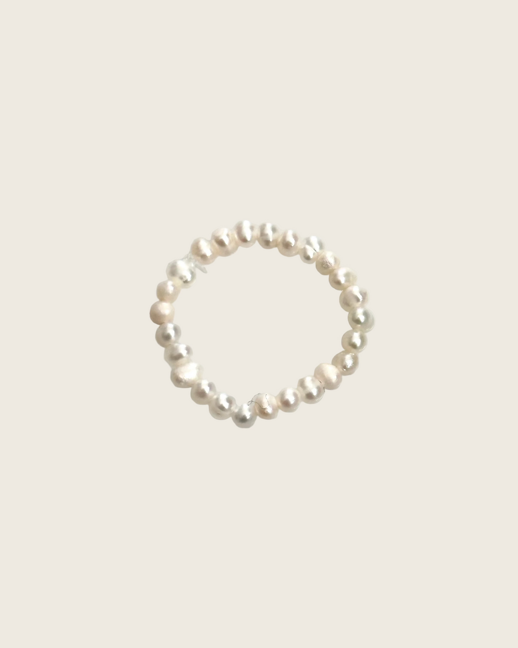 A delicate beaded ring featuring small, irregular white and pale pink pearls separated by tiny silver spacer beads, displayed on a clean, light gray background.