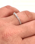 A delicate beaded ring made of small, faceted clear stones worn on a person's finger, shown against a plain white background.